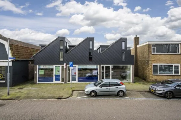 Modern kantoorpand aan de Raadhuisstraat met opvallend zadeldak en geparkeerde auto's voor de deur.