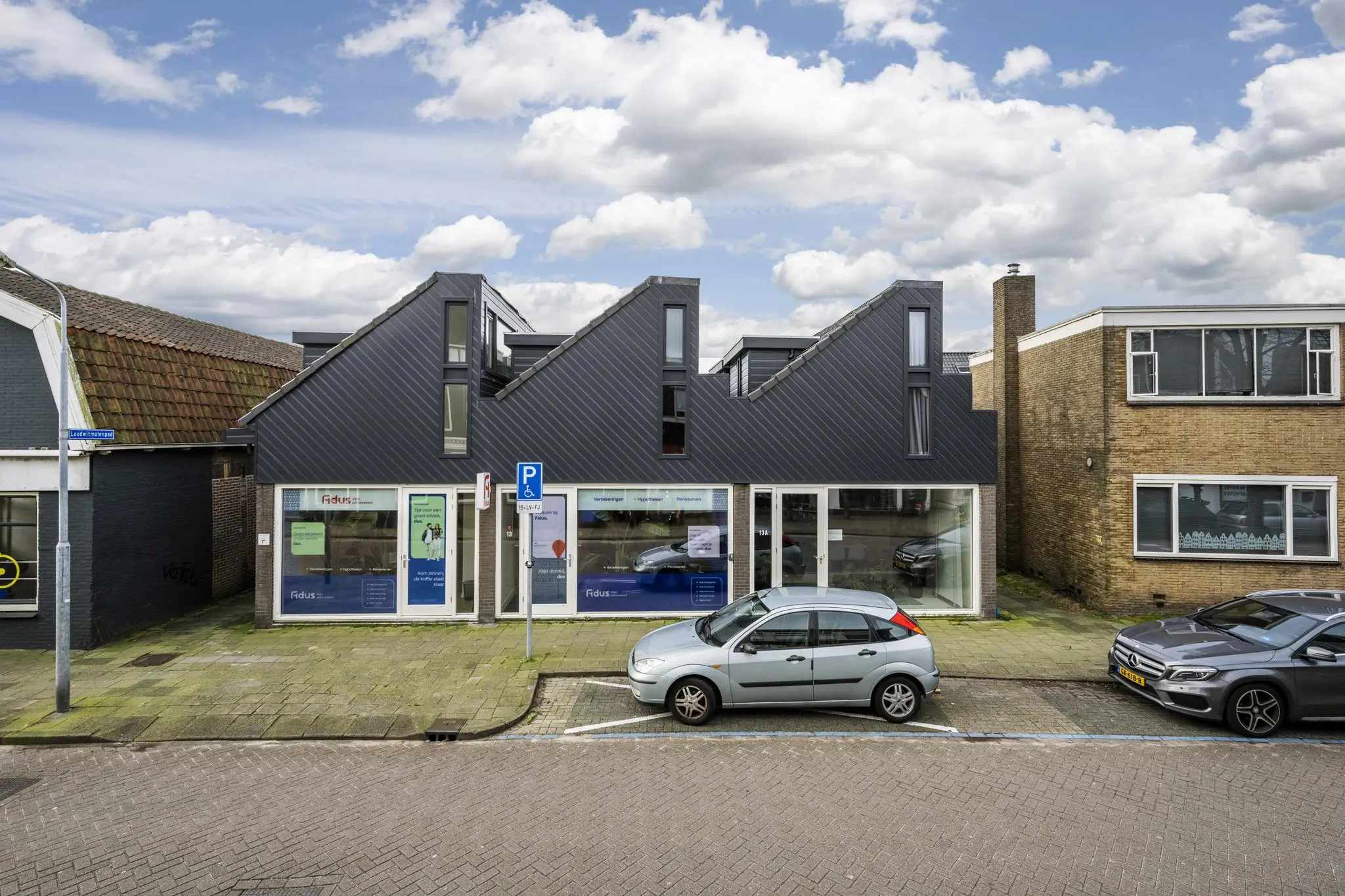 Modern kantoorpand aan de Raadhuisstraat met opvallend zadeldak en geparkeerde auto's voor de deur.