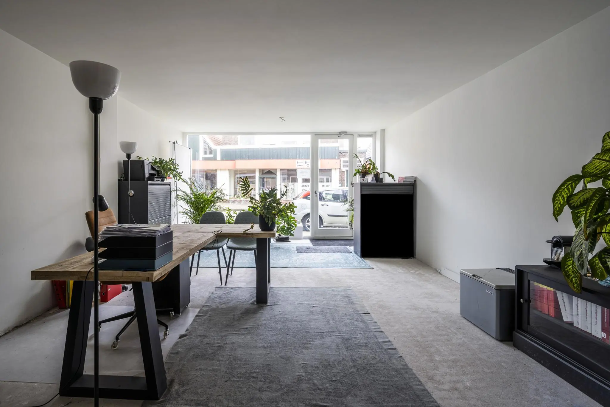 Modern ingericht kantoor aan de Raadhuisstraat met houten bureau, planten en grote ramen aan de straatzijde.