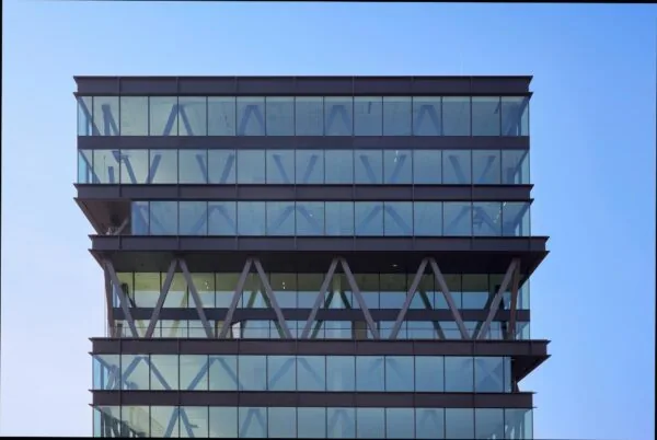 Moderne kantoorverdiepingen van een glazen kantoorpand aan de Joan Muyskenweg tegen een heldere blauwe lucht.