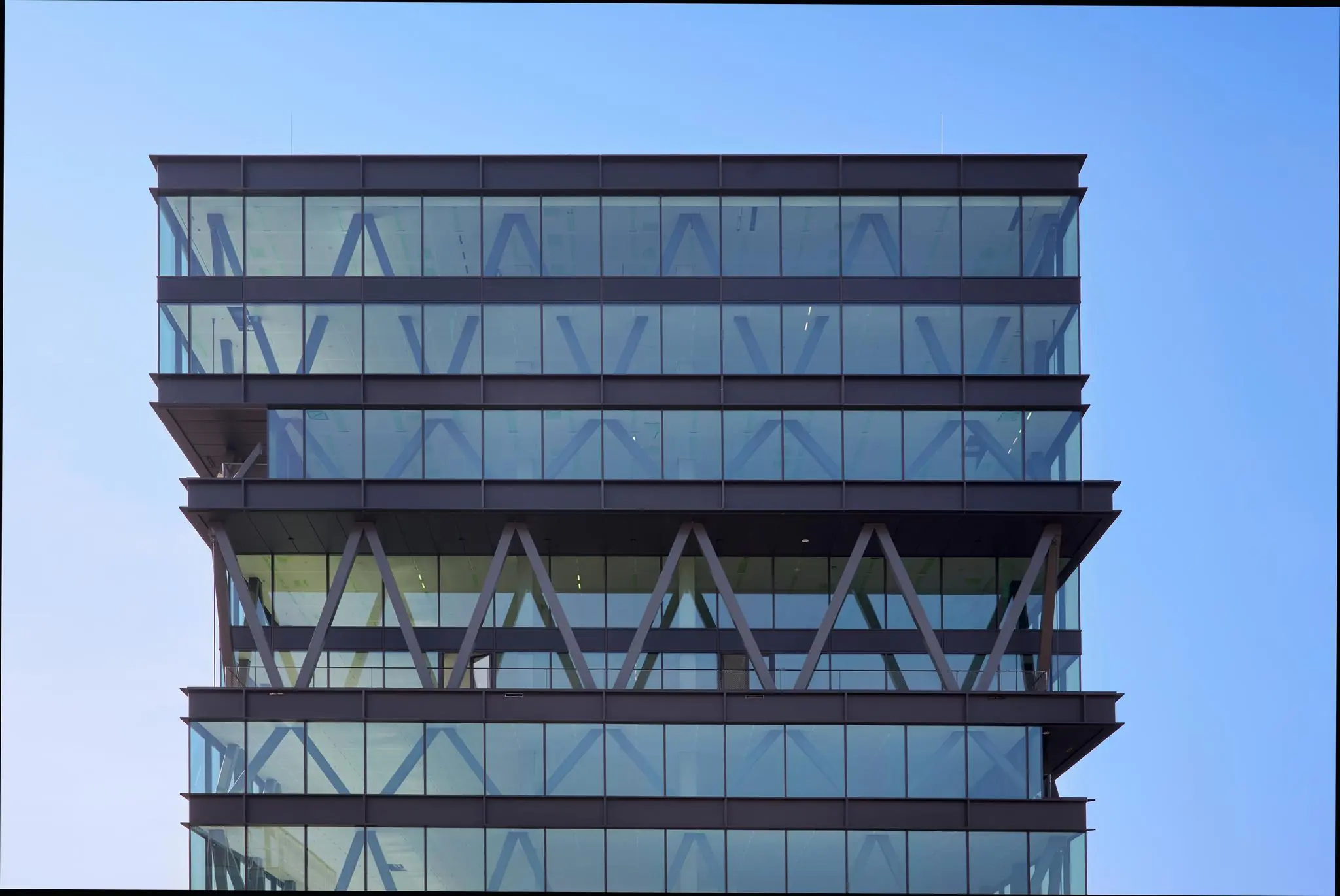 Moderne kantoorverdiepingen van een glazen kantoorpand aan de Joan Muyskenweg tegen een heldere blauwe lucht.
