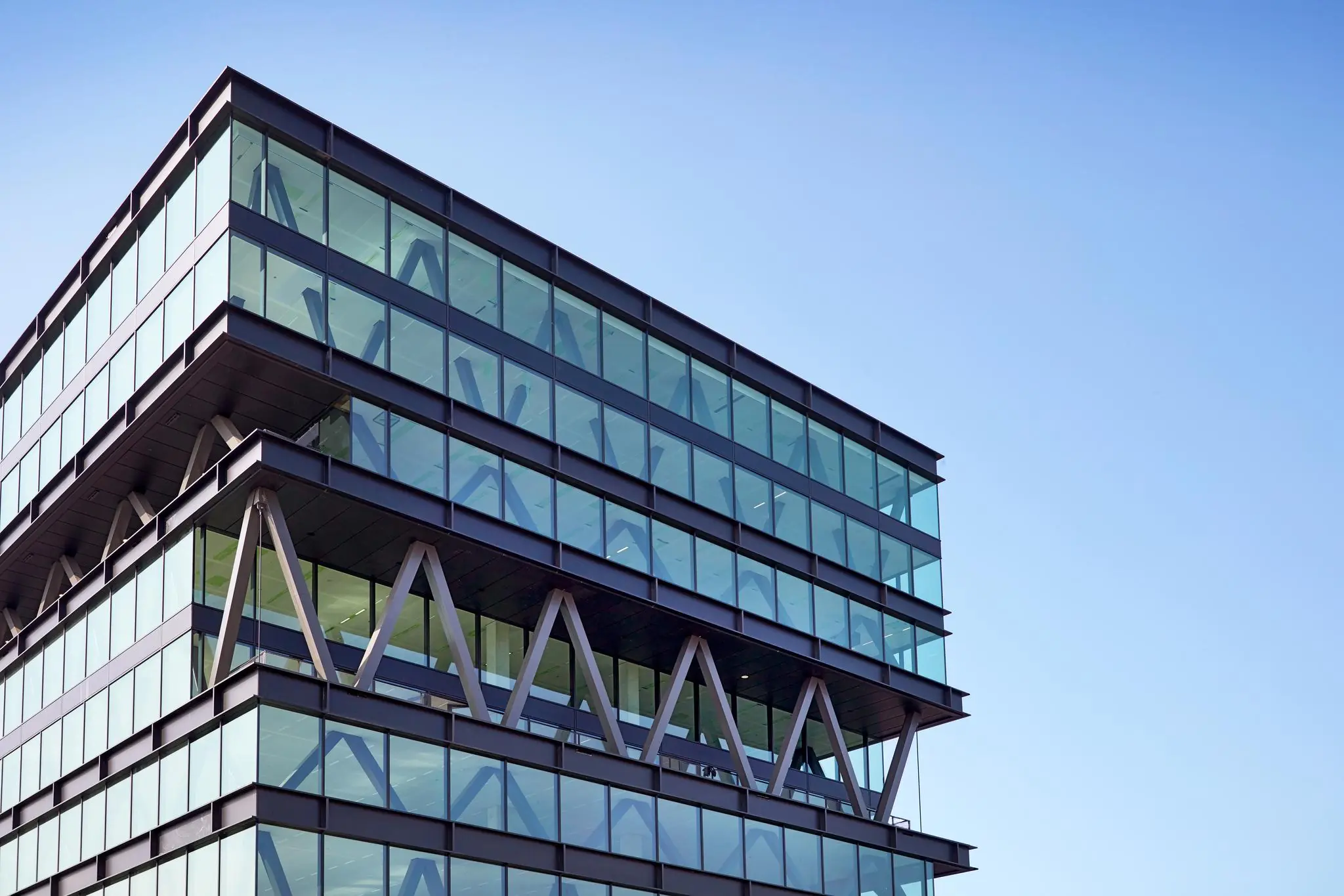 Modern kantoorgebouw met glazen gevel en opvallende driehoekige draagconstructie aan de Joan Muyskenweg.