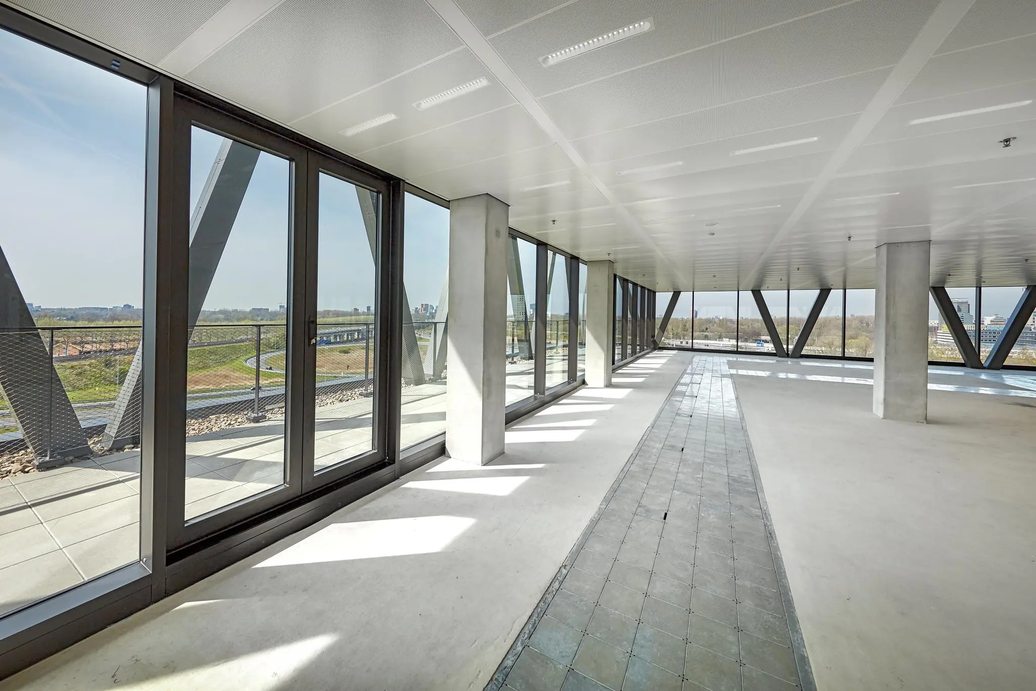 Lichte, lege kantoorruimte aan de Joan Muyskenweg met grote ramen en uitzicht op de omgeving.