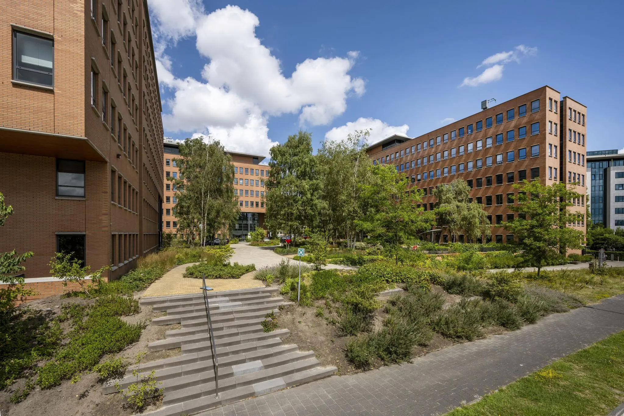 Twee kantoorgebouwen aan de Hullenbergweg met een groene binnentuin en wandelpaden tussen de gebouwen.