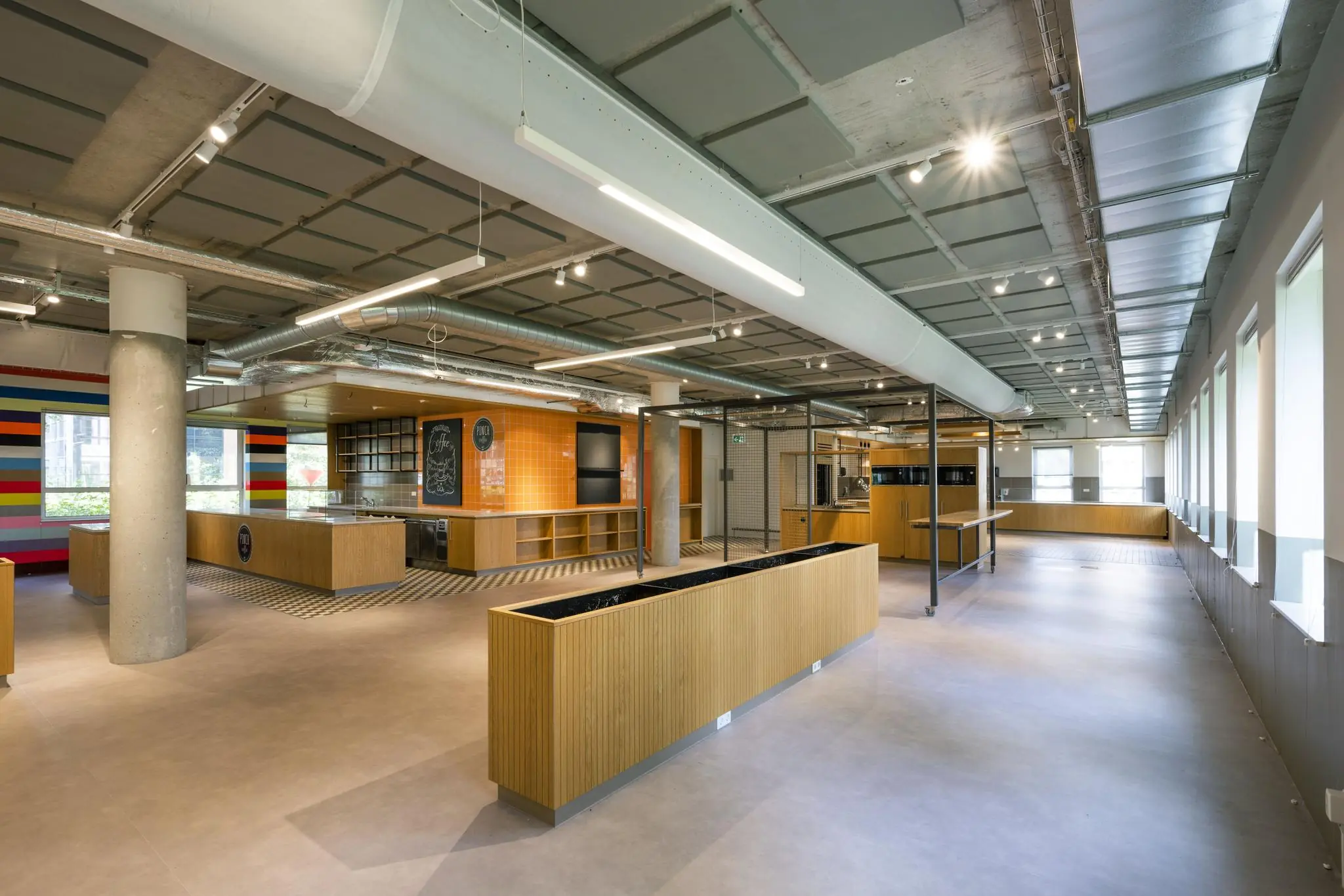 Moderne, open kantoorruimte aan de Hullenbergweg met een industriële uitstraling en een keuken met kleurrijke accentmuur.