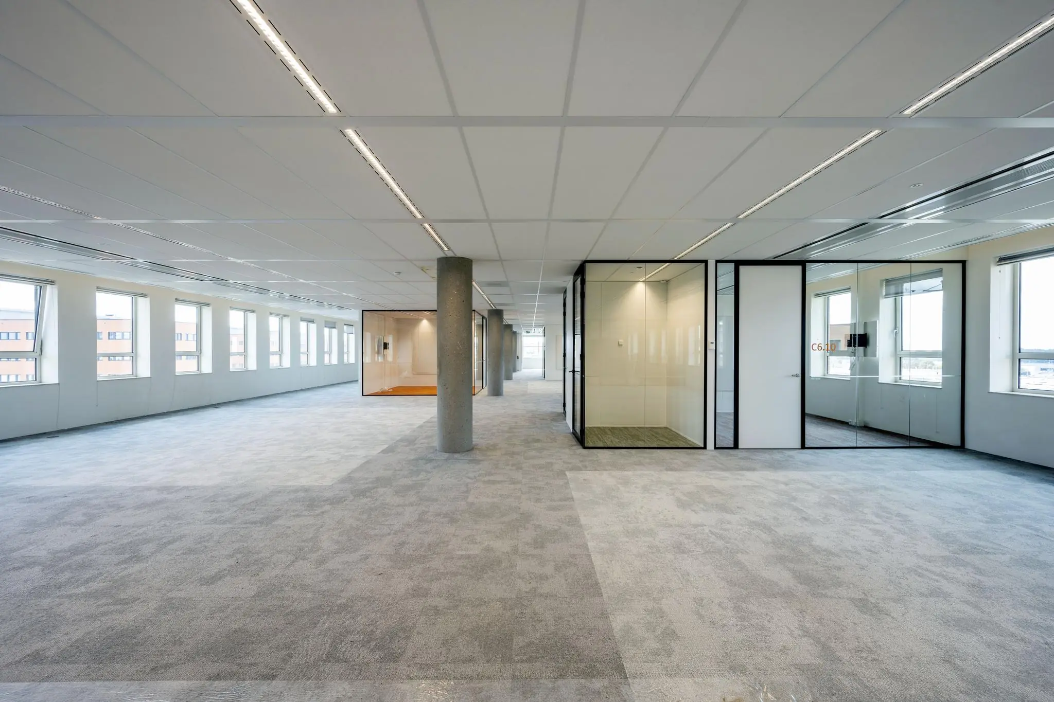 Ruime, moderne kantoorruimte aan de Hullenbergweg met grote ramen en glazen vergaderruimtes.