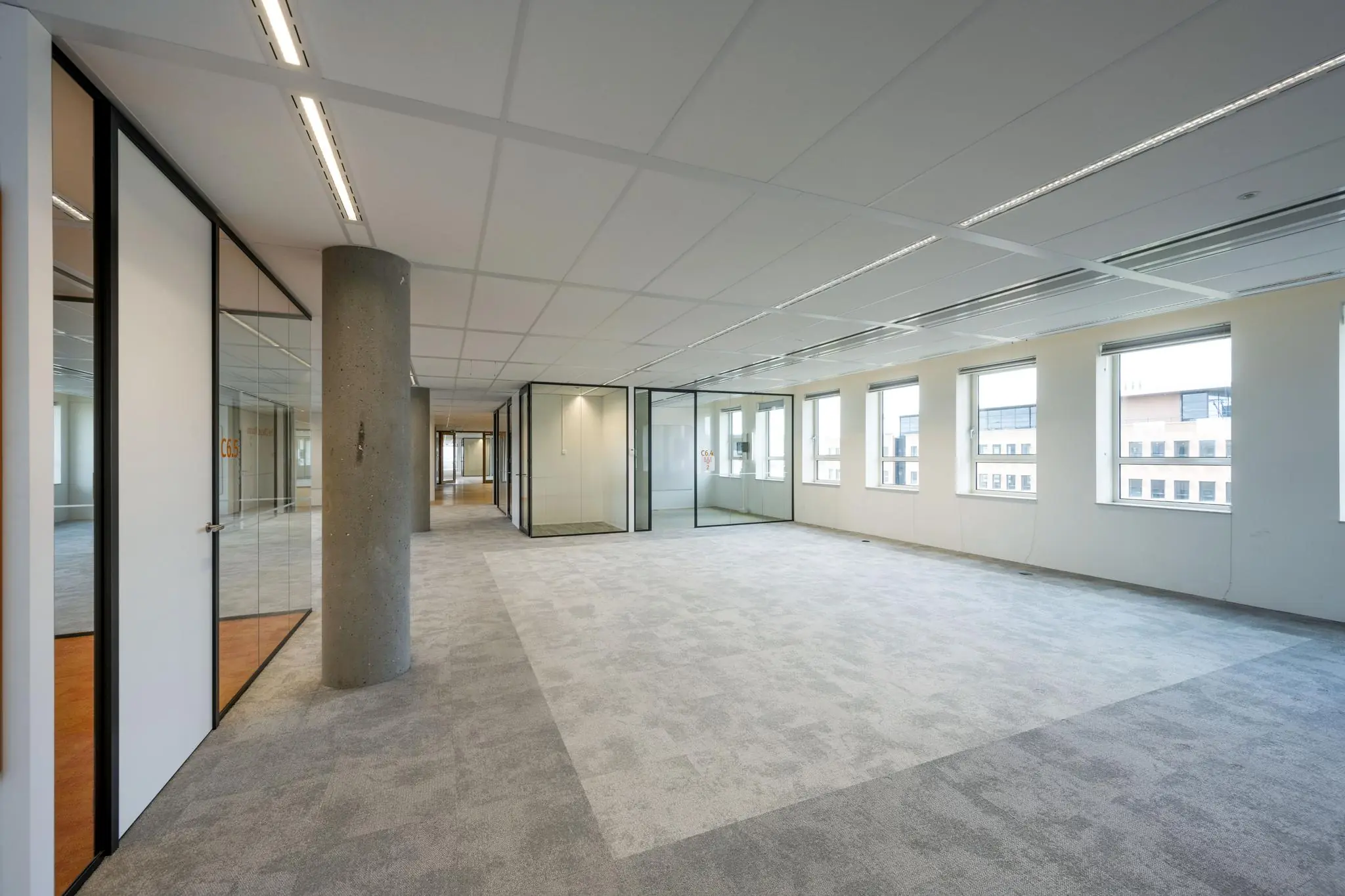 Licht en modern kantoorpand aan de Hullenbergweg met glazen vergaderruimtes en grote ramen.