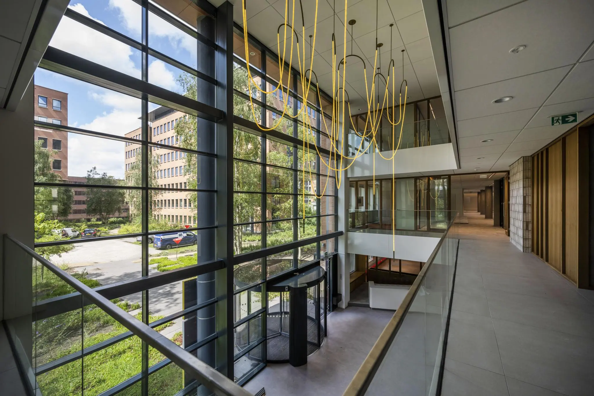 Moderne kantoorruimte aan de Hullenbergweg met glazen gevel, gele hangverlichting en uitzicht op omliggende gebouwen.