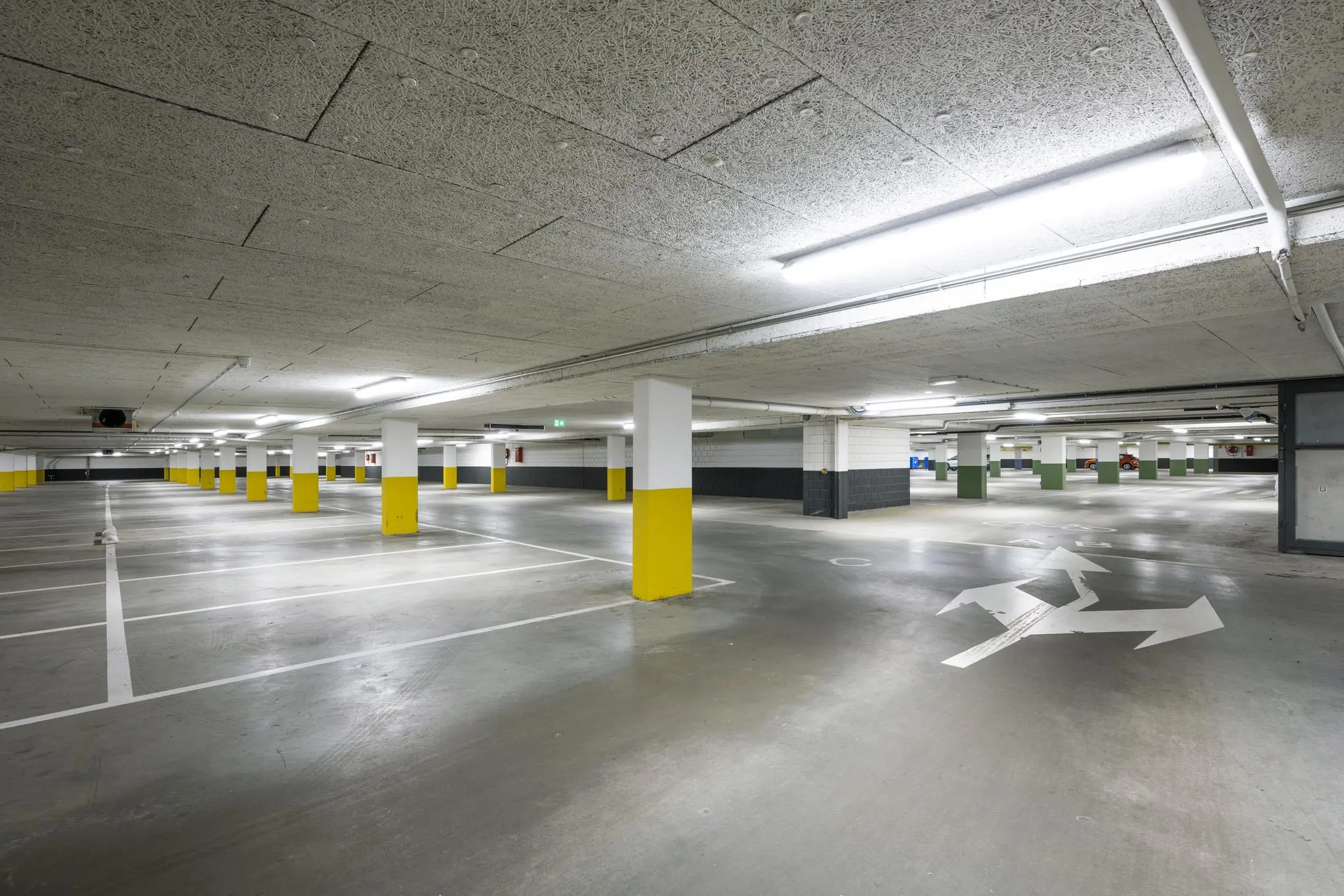 Lege en goed verlichte parkeergarage aan de Hullenbergweg met witte belijning en geel gemarkeerde pilaren.