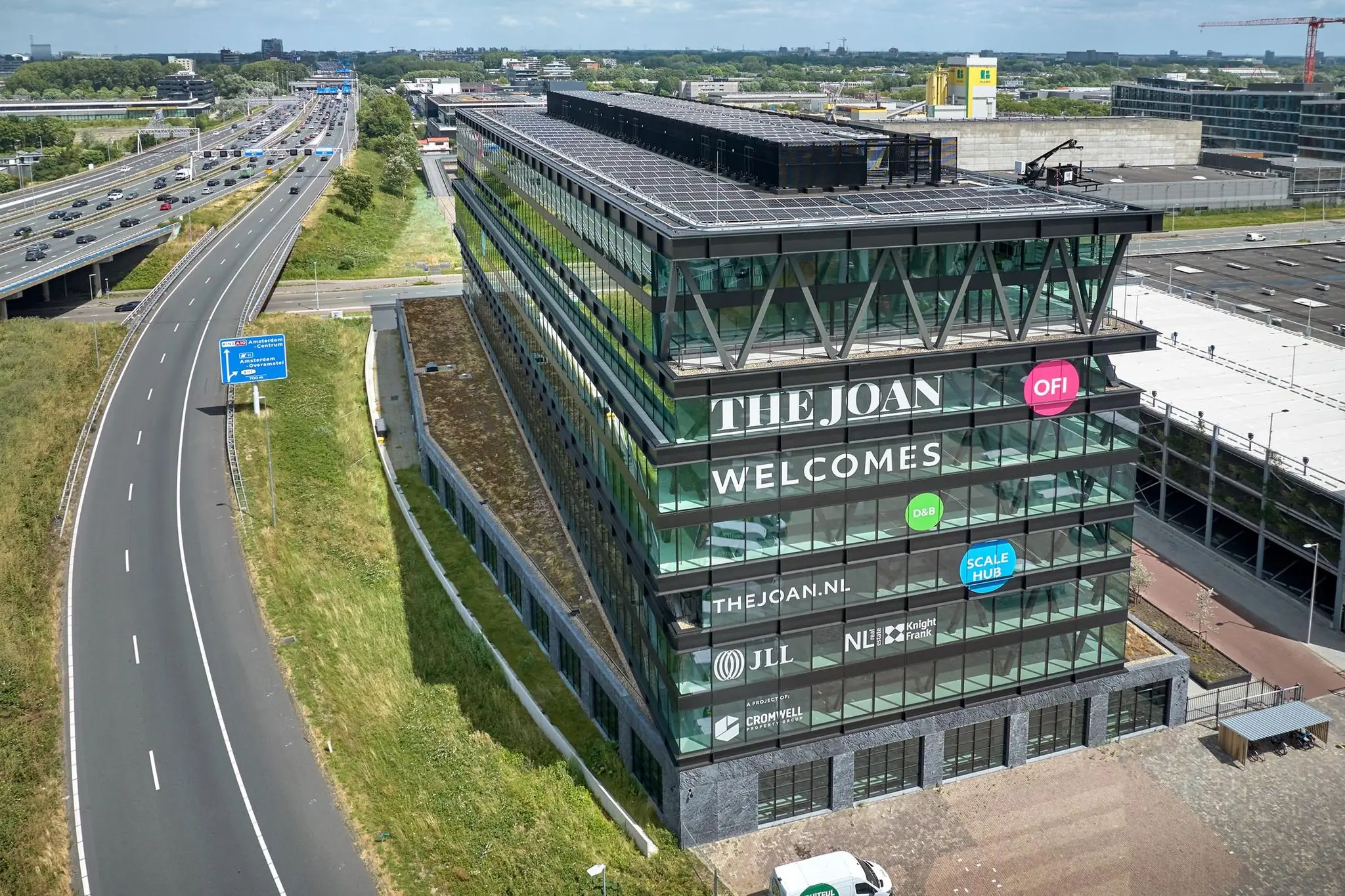 Kantoorgebouw "The Joan" aan de Joan Muyskenweg in Amsterdam, gelegen naast de snelweg en voorzien van zonnepanelen op het dak.
