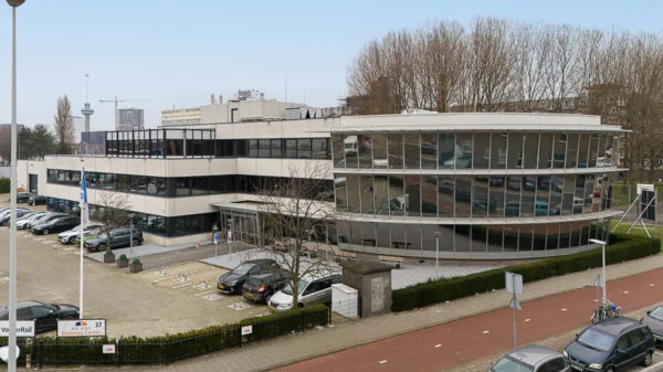 Kantoorgebouw aan de Sluisjesdijk in Rotterdam met parkeerplaats en moderne glazen gevel.