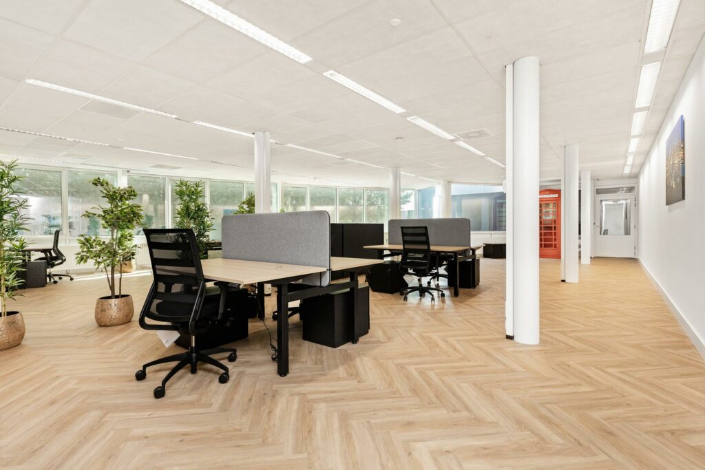 Modern en licht kantoorpand aan de Sluisjesdijk met flexwerkplekken, planten en een opvallende rode telefooncel.