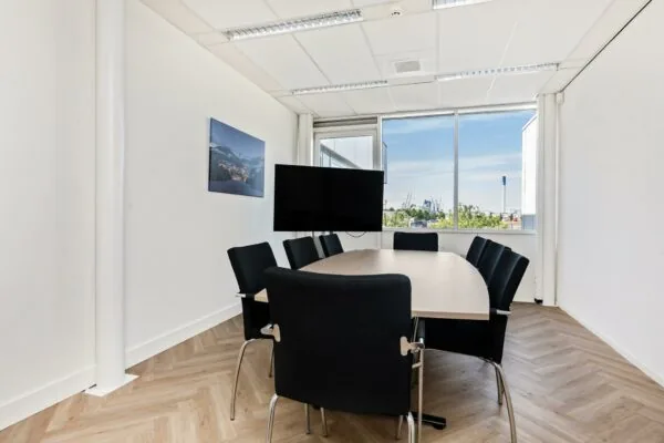Vergaderruimte aan de Sluisjesdijk met ovale tafel, acht stoelen, tv-scherm en uitzicht op de haven.