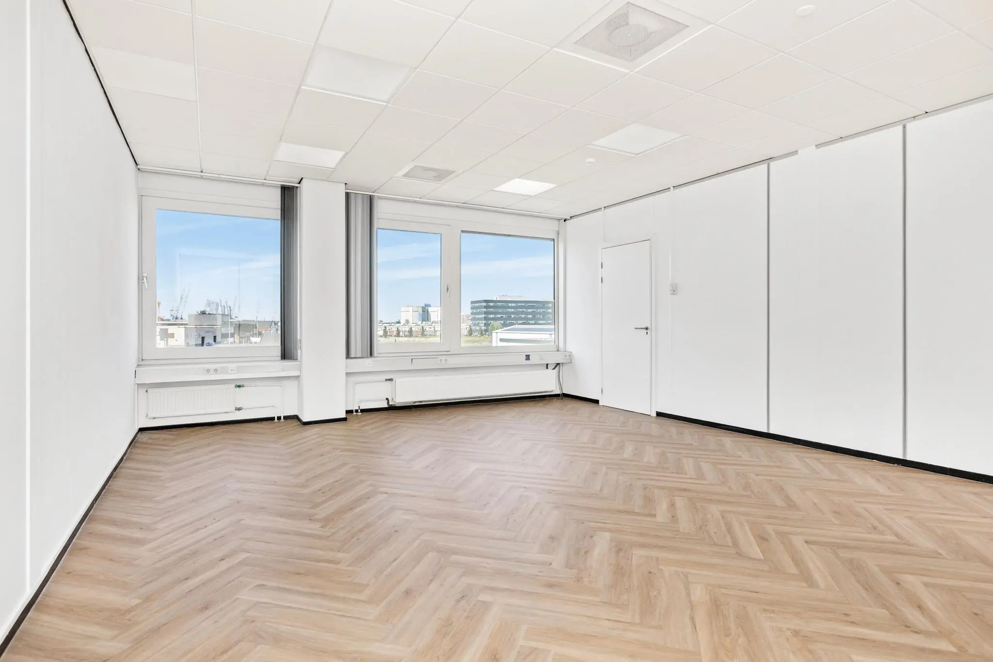 Lichte, lege kantoorruimte aan de Sluisjesdijk met visgraatvloer en grote ramen.