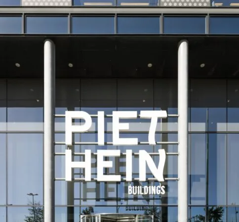 Glazen gevel van het Piet Hein Buildings-kantoor met grote witte belettering op de ingang.