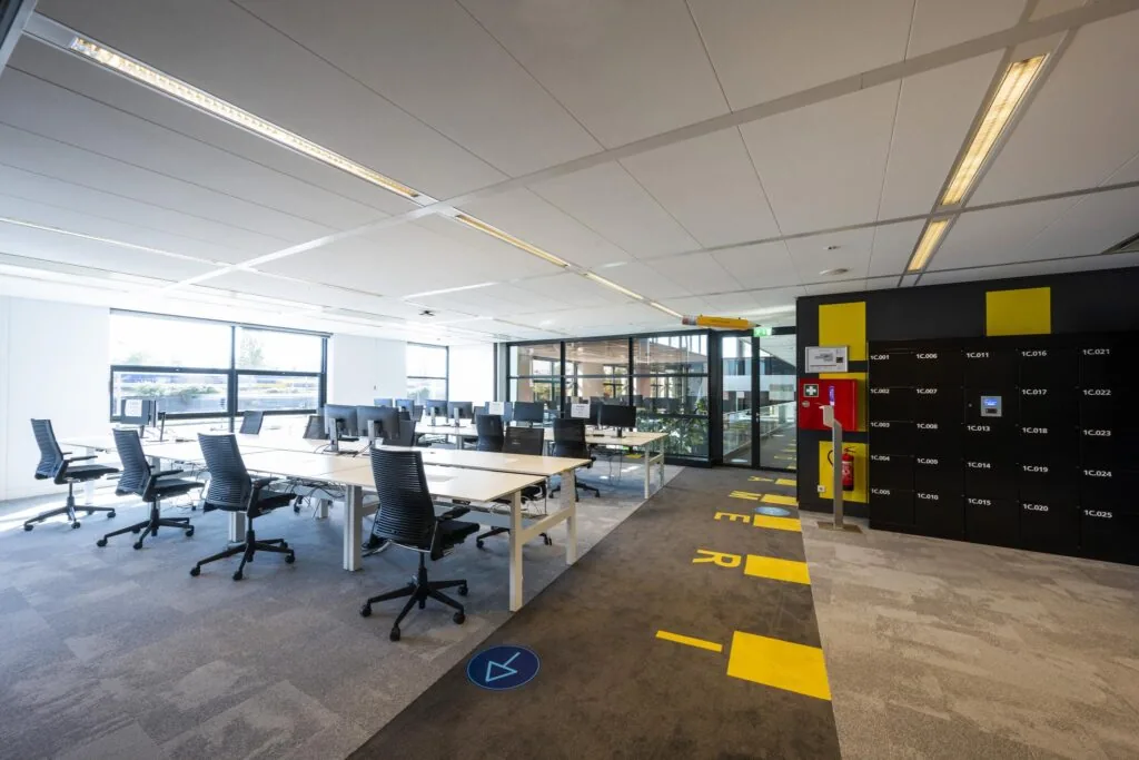 Moderne kantoortuin op de Piet Heinkade met gedeelde werkplekken, bureaustoelen en kluisjeswand.
