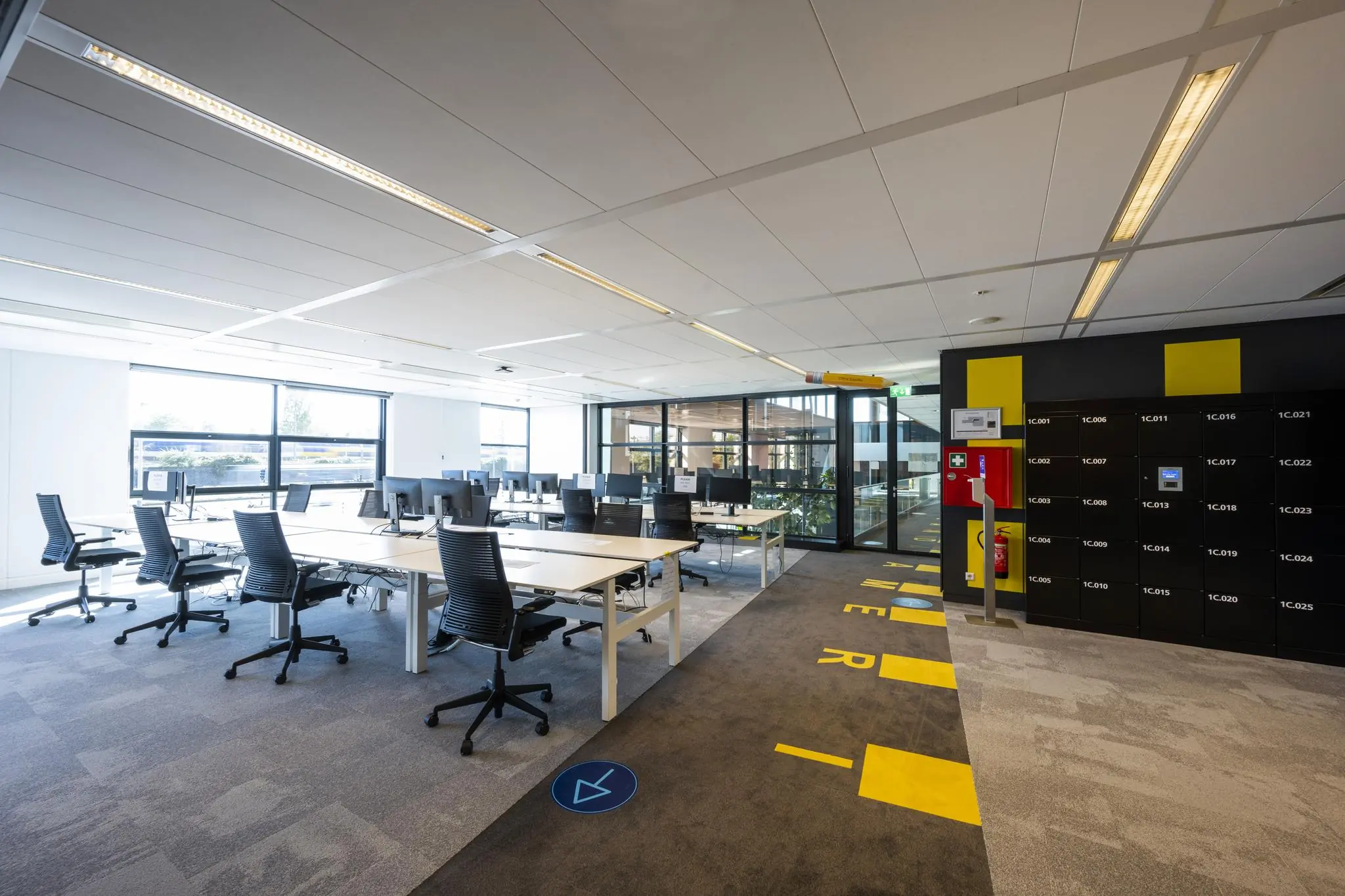 Moderne kantoortuin op de Piet Heinkade met gedeelde werkplekken, bureaustoelen en kluisjeswand.