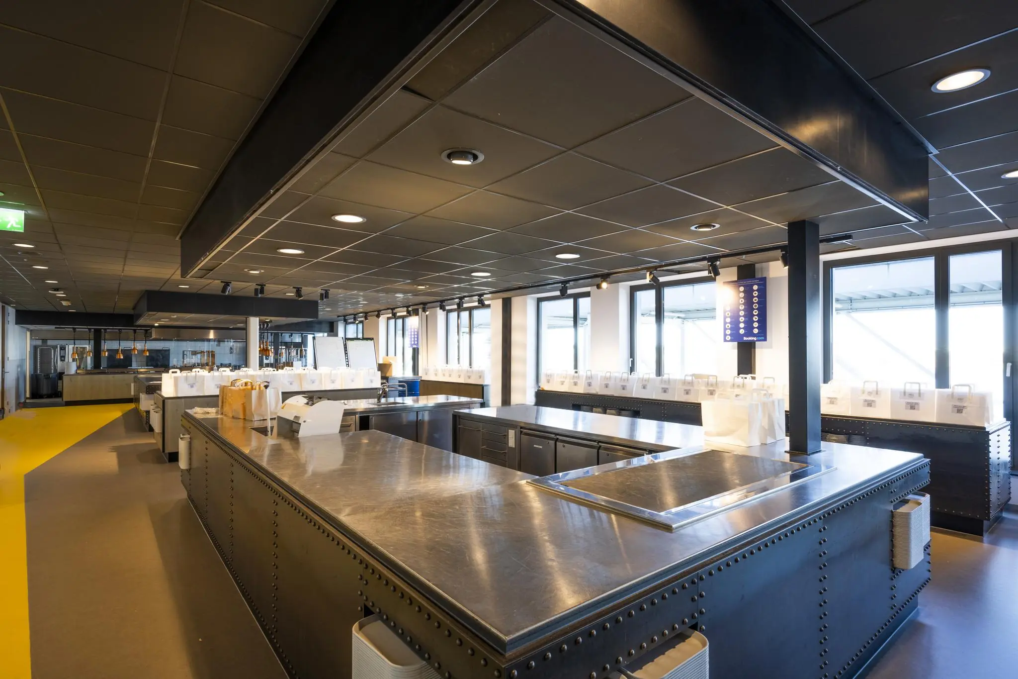 Moderne, ruim opgezette keuken in een bedrijfsrestaurant aan de Piet Heinkade met roestvrijstalen werkbladen en uitgestalde lunchpakketten.