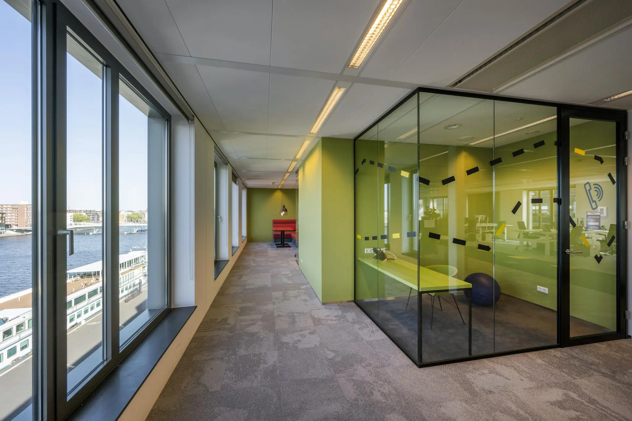 Moderne kantoorruimte aan de Piet Heinkade met glazen vergaderruimte, felle kleuren en uitzicht op het water.