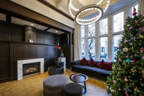 Stijlvolle woonkamer aan de Honthorststraat met moderne haard, grote ramen en versierde kerstboom.