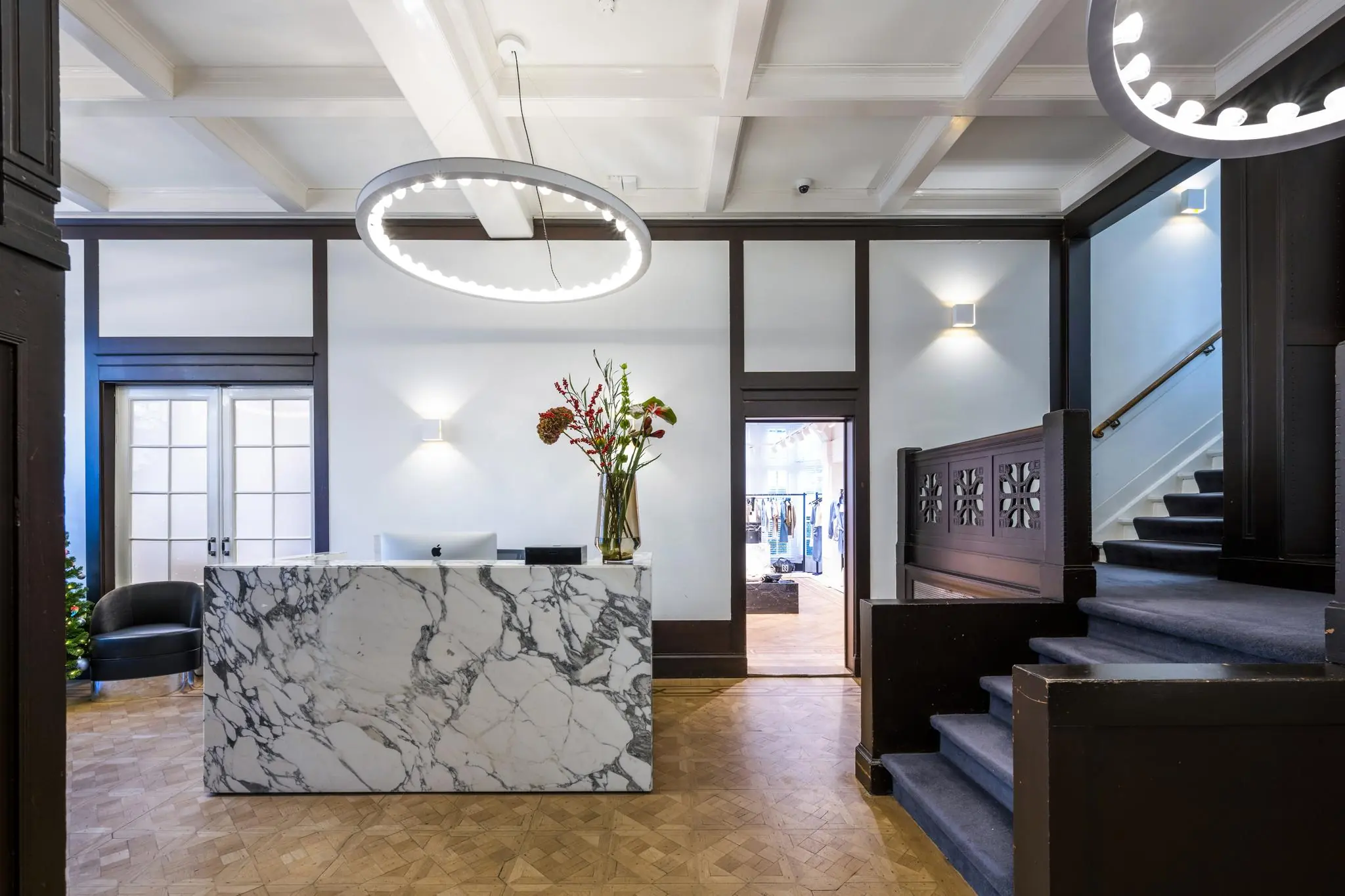 Moderne ontvangsthal aan de Honthorststraat met marmeren balie, designverlichting en trap naar boven.