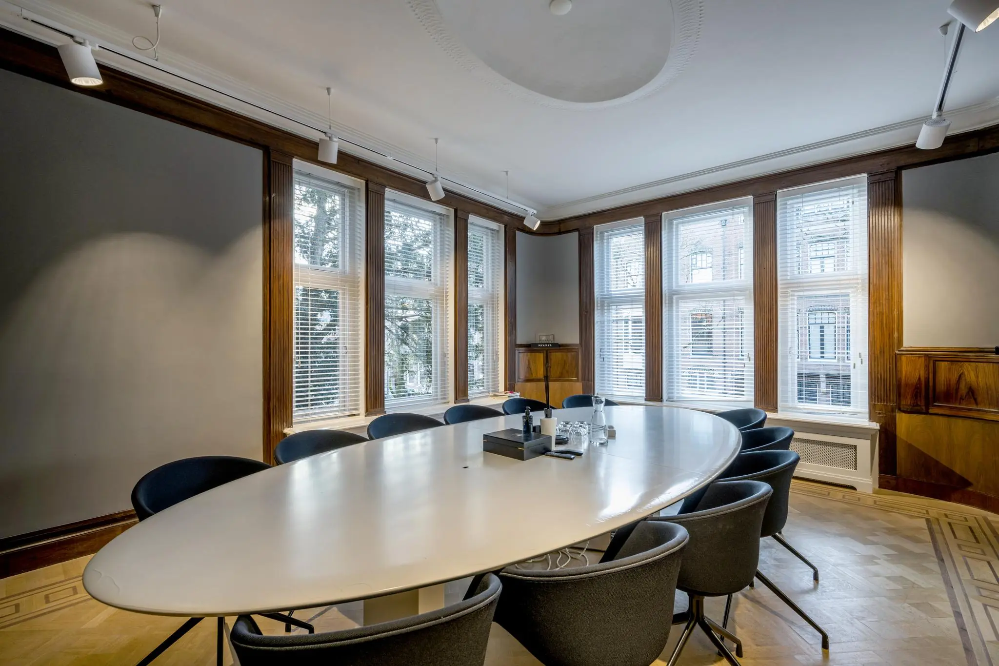 Vergaderruimte met ovale tafel, moderne stoelen en grote ramen aan de Honthorststraat.
