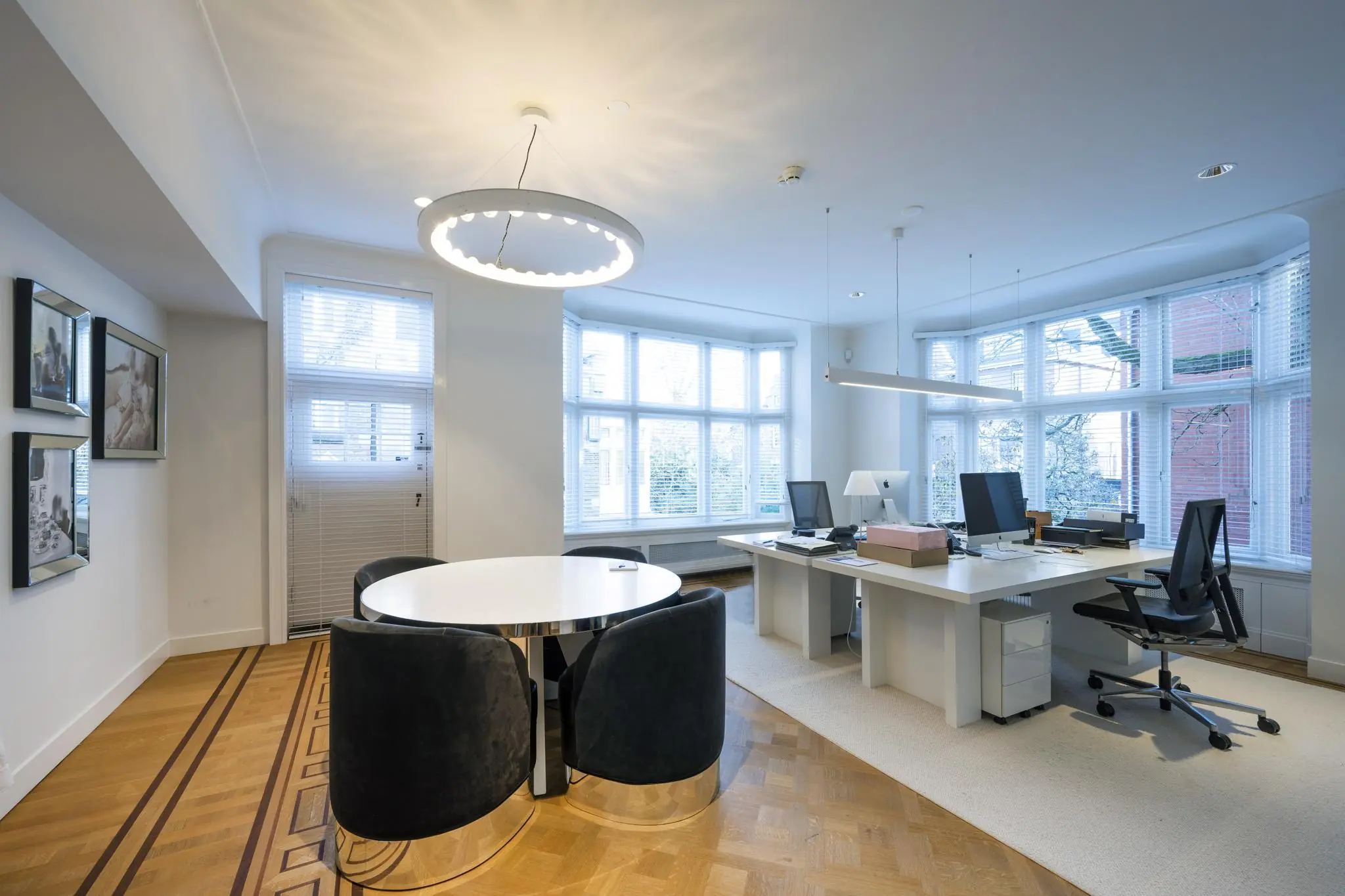 Modern ingericht kantoor aan de Honthorststraat met grote ramen, strakke bureaus en een ronde vergadertafel.