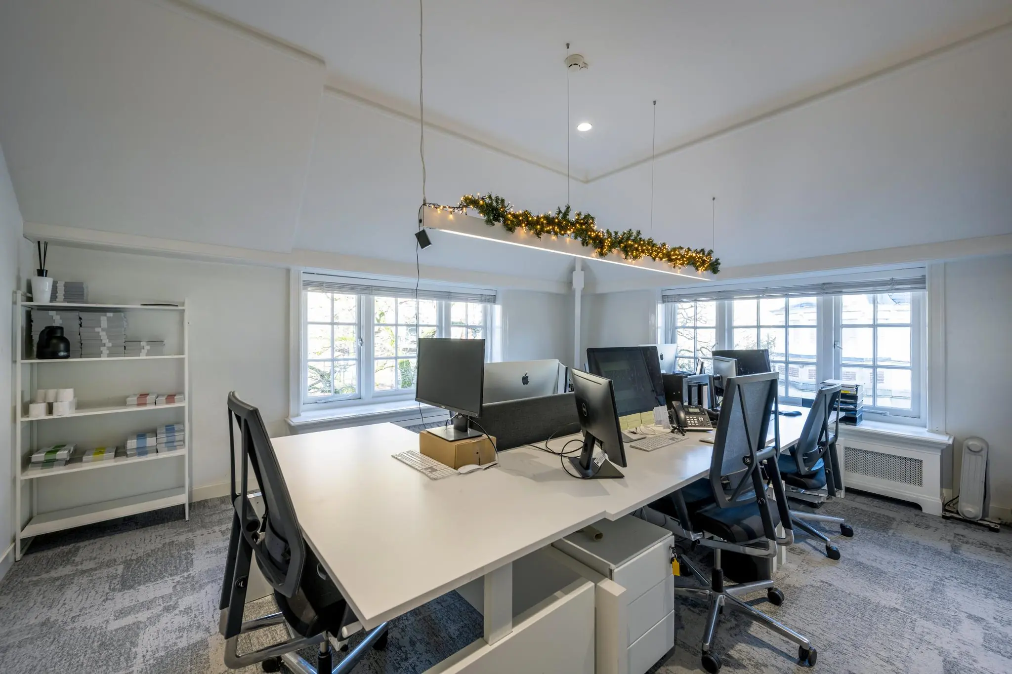 Modern kantoor aan de Honthorststraat met bureaus, computers en kerstverlichting aan het plafond.