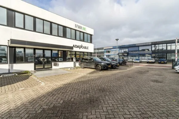 Bedrijfsgebouwen aan de Savannahweg met geparkeerde auto's op de parkeerplaats voor Adaptable, Eager.One en Vitec/Vigr.