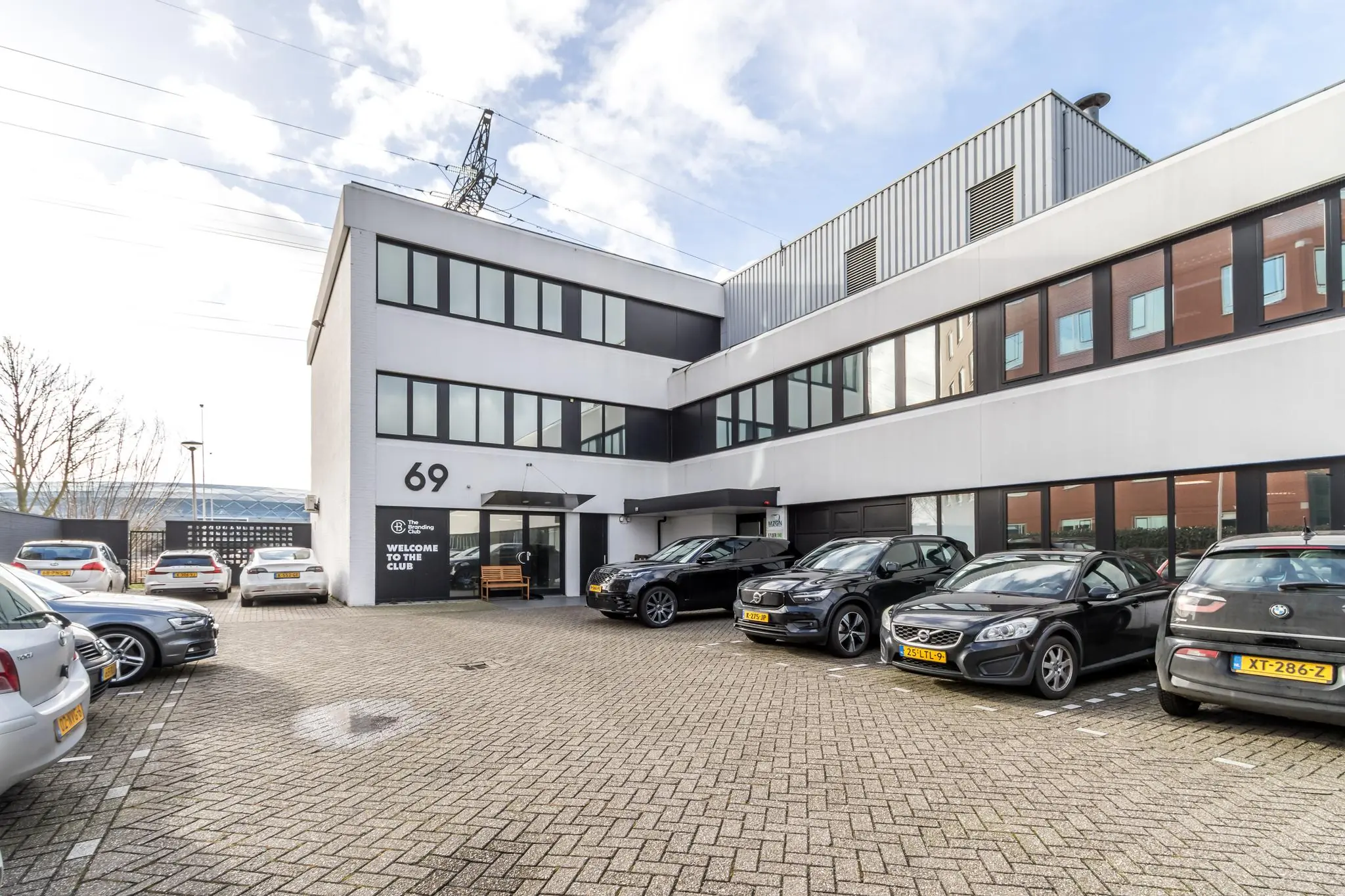 Vooraanzicht van een modern kantoorpand aan de Savannahweg 69 met geparkeerde auto’s op de parkeerplaats.