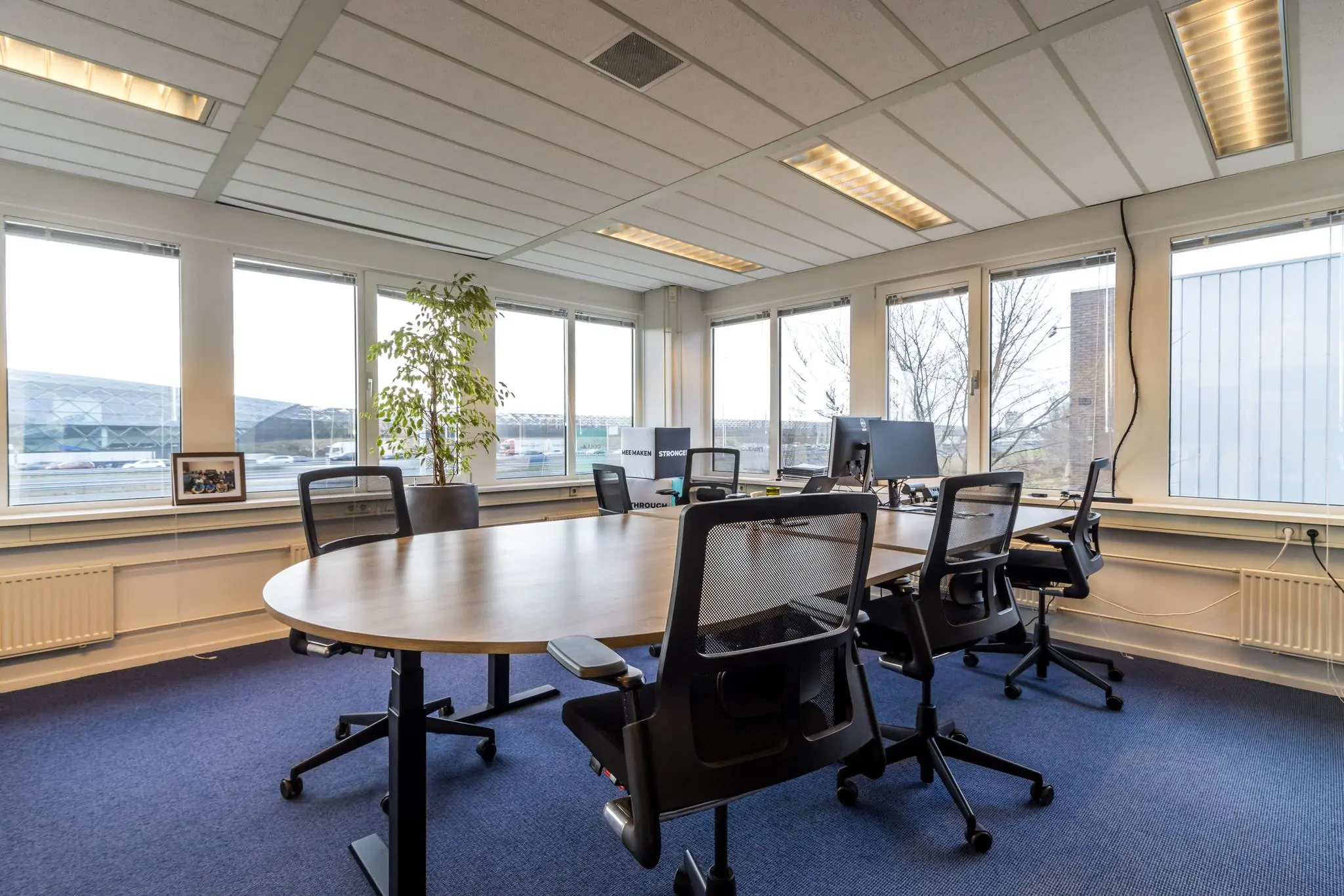 Moderne kantoorruimte aan de Savannahweg met bureaus, bureaustoelen en computers, omringd door grote ramen met uitzicht op buiten.