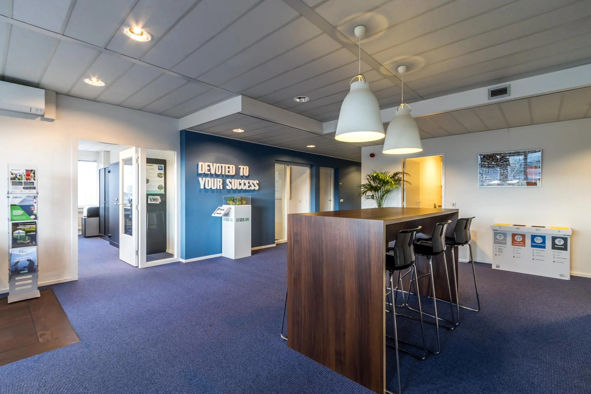 Moderne kantoorruimte aan de Savannahweg met hoge tafel, zitplekken en een muur met de tekst "Devoted to your success".