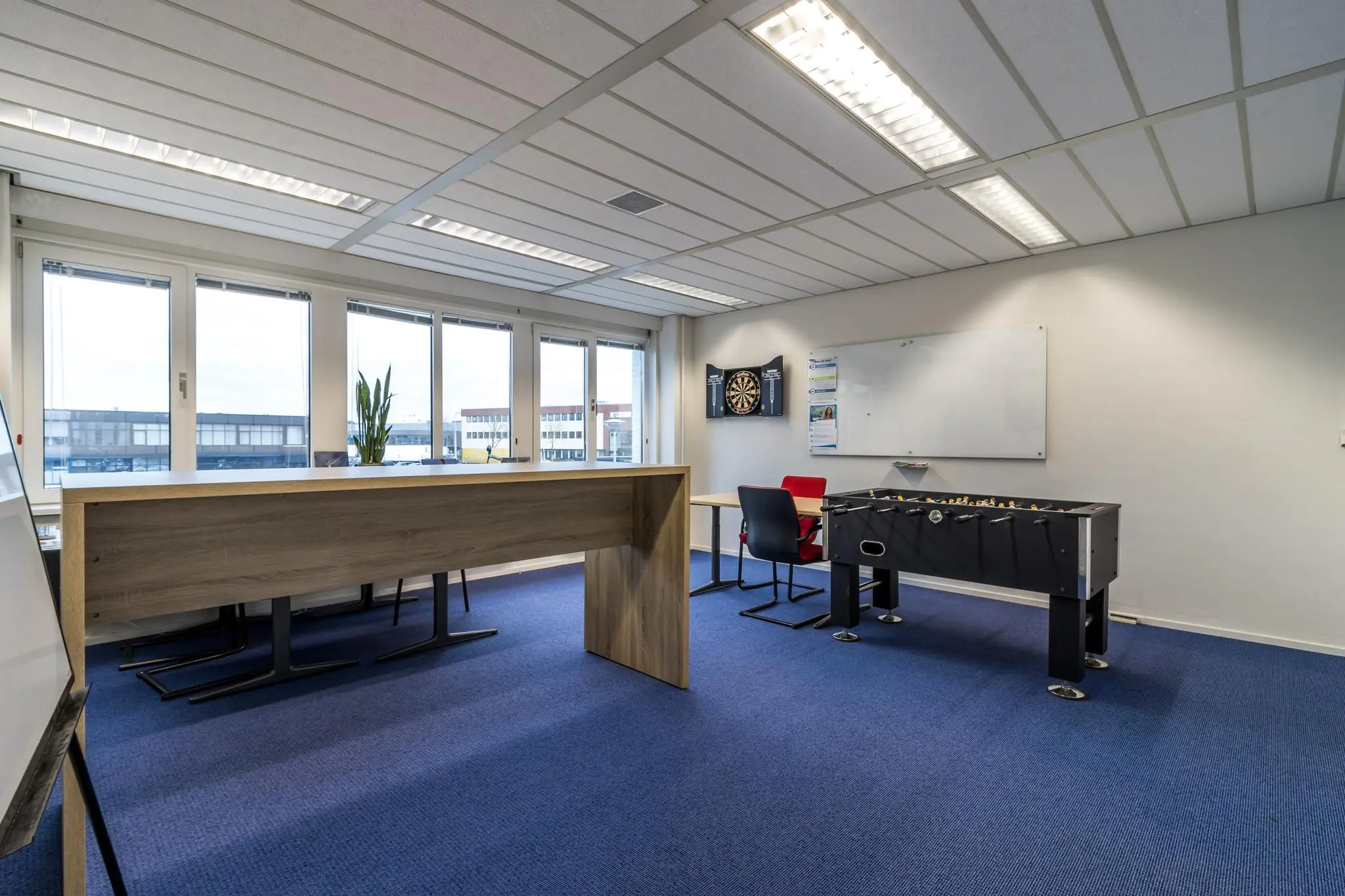 Moderne kantoorruimte aan de Savannahweg met grote ramen, een werktafel, dartbord en tafelvoetbaltafel.