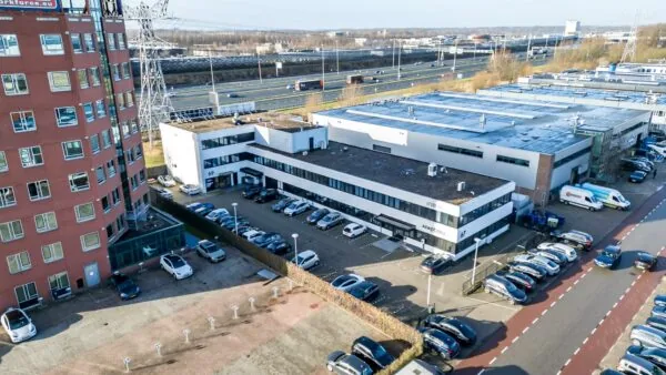 Luchtfoto van een kantoorgebouw aan de Savannahweg in een bedrijventerrein met parkeerplaatsen en nabijgelegen snelweg.