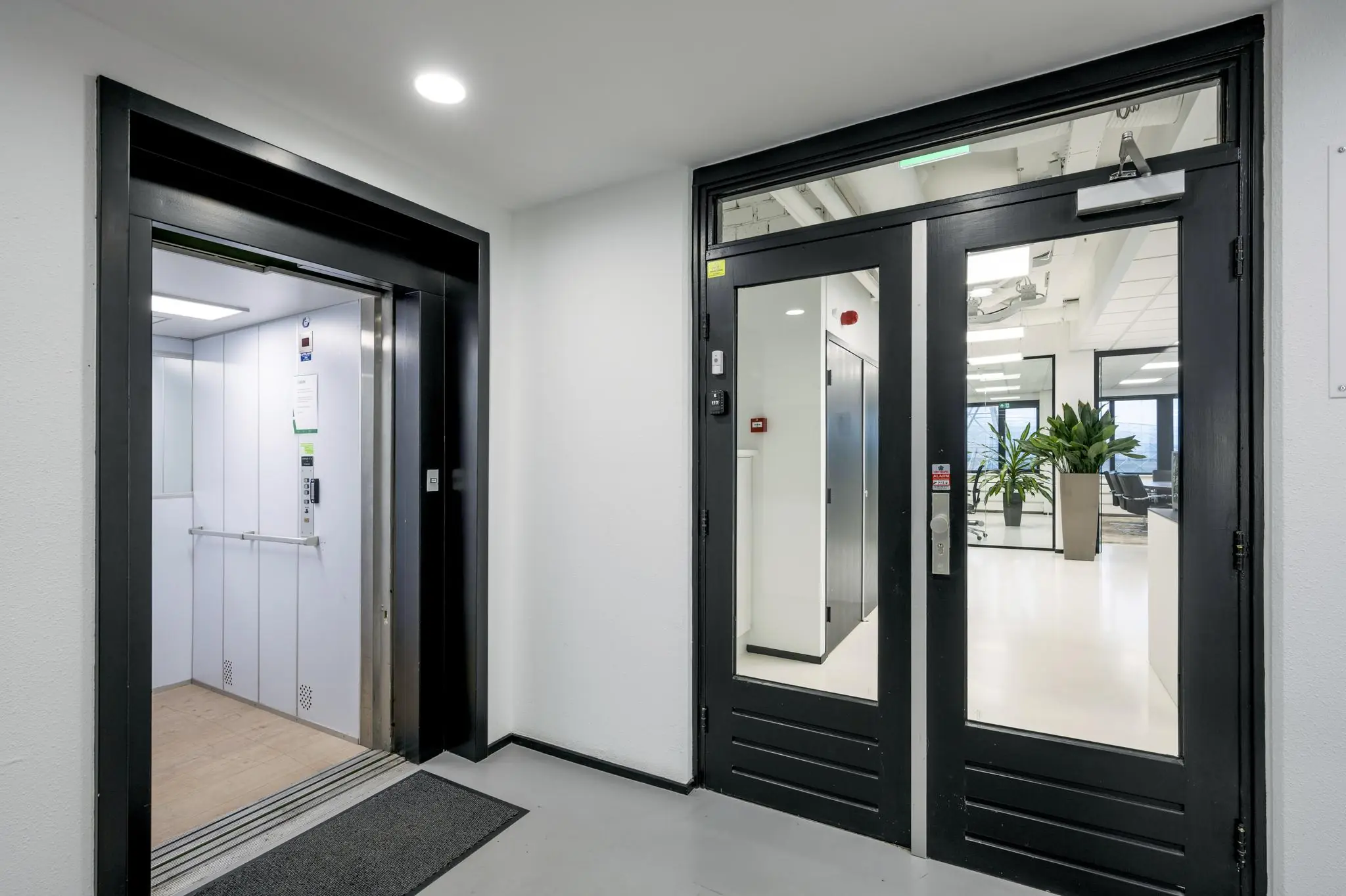 Entreehal met een open lift en glazen deur naar een modern kantoor aan de Savannahweg.