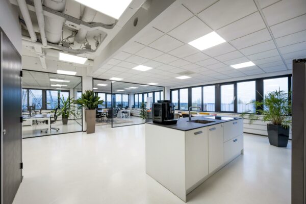 Moderne en lichte kantooruimte aan de Savannahweg met glazen vergaderruimtes, een kitchenette en grote ramen.
