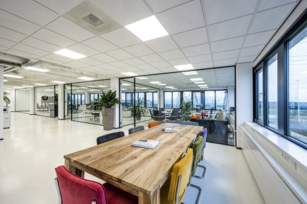Modern open kantoorinterieur aan de Savannahweg met een houten vergadertafel en kleurrijke stoelen.