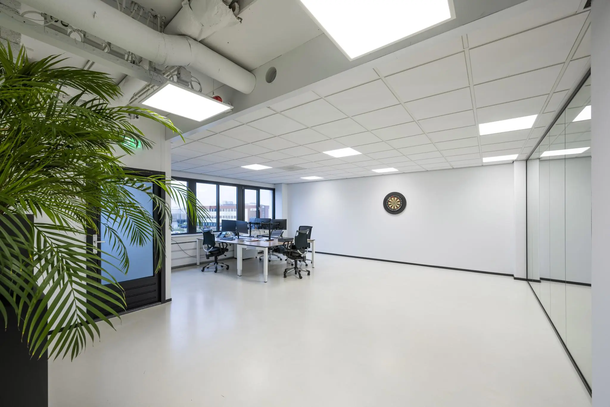 Modern kantoorinterieur aan de Savannahweg met werkplekken, dartbord en grote ramen.