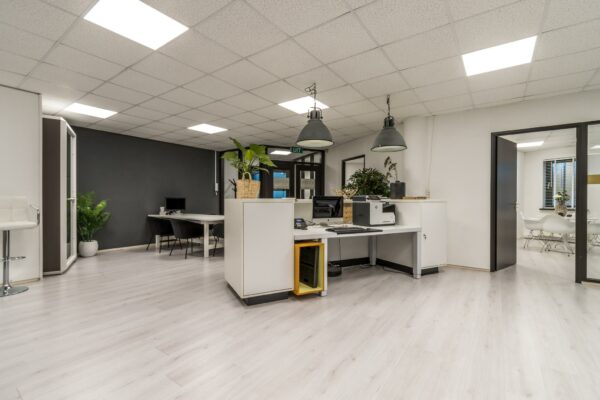 Modern en licht ingericht kantoorinterieur aan de Koningsweg met werkplekken, vergaderruimte en veel planten.