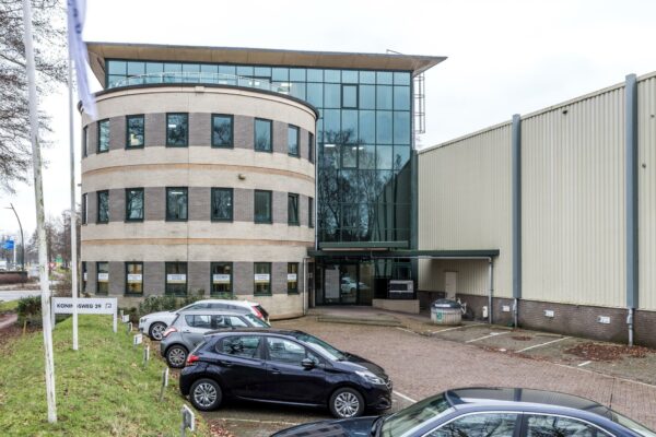 Kantoorpand aan de Koningsweg 29 met parkeervakken en meerdere geparkeerde auto's op de voorgrond.