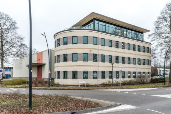 Modern kantoorgebouw aan de Koningsweg met afgeronde hoek en grote ramen, gelegen naast een rotonde.