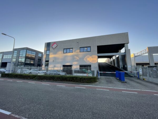Voorzijde van een modern bedrijfsgebouw van APK met een hellingbaan en slagboom.