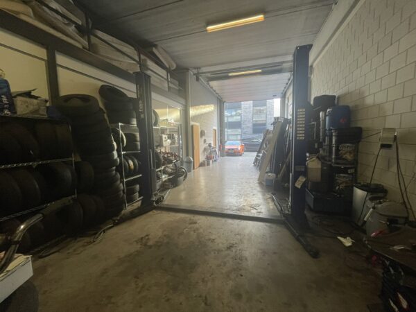 Garage met een lift en auto's op de achtergrond