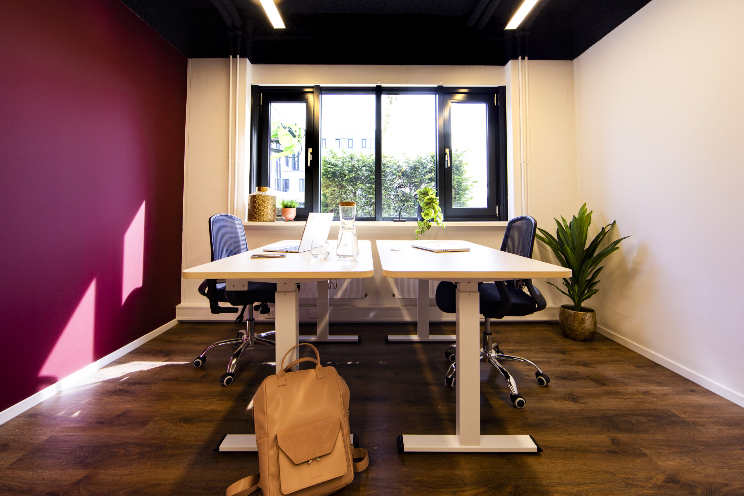 Een modern ingericht kantoor in Woerden met twee bureaus, stoelen en een rugzak op de vloer.