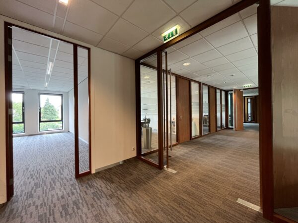 Moderne kantoorruimte aan de Groenekanseweg met glazen wanden, tapijtvloer en uitzicht op groen.