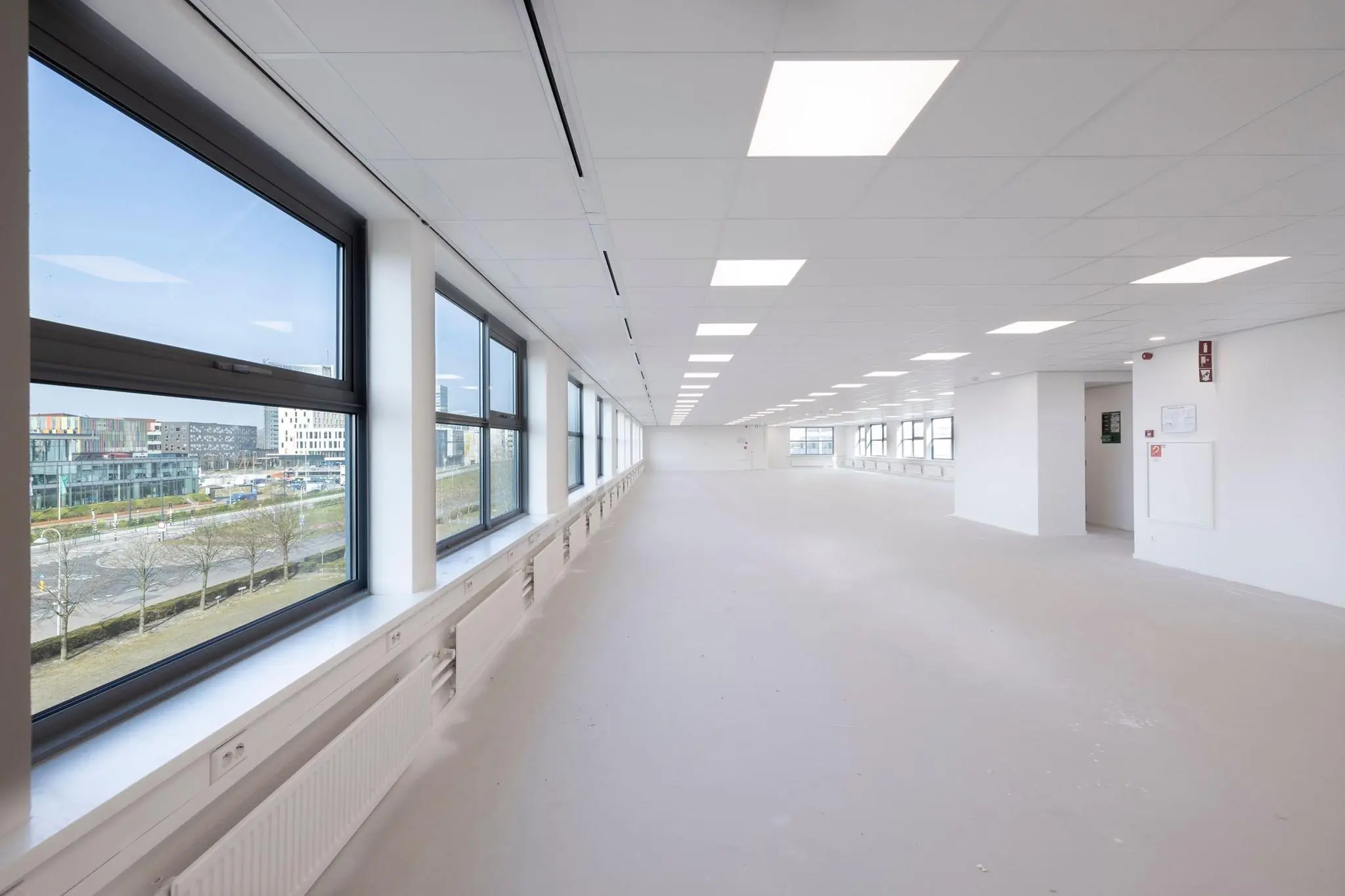 Licht en modern leeg kantoorinterieur aan de Spicalaan met grote ramen en systeemplafond.