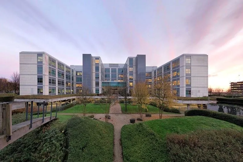 Modern kantoorgebouw aan de Spicalaan met symmetrische architectuur en aangelegde tuin op de voorgrond.