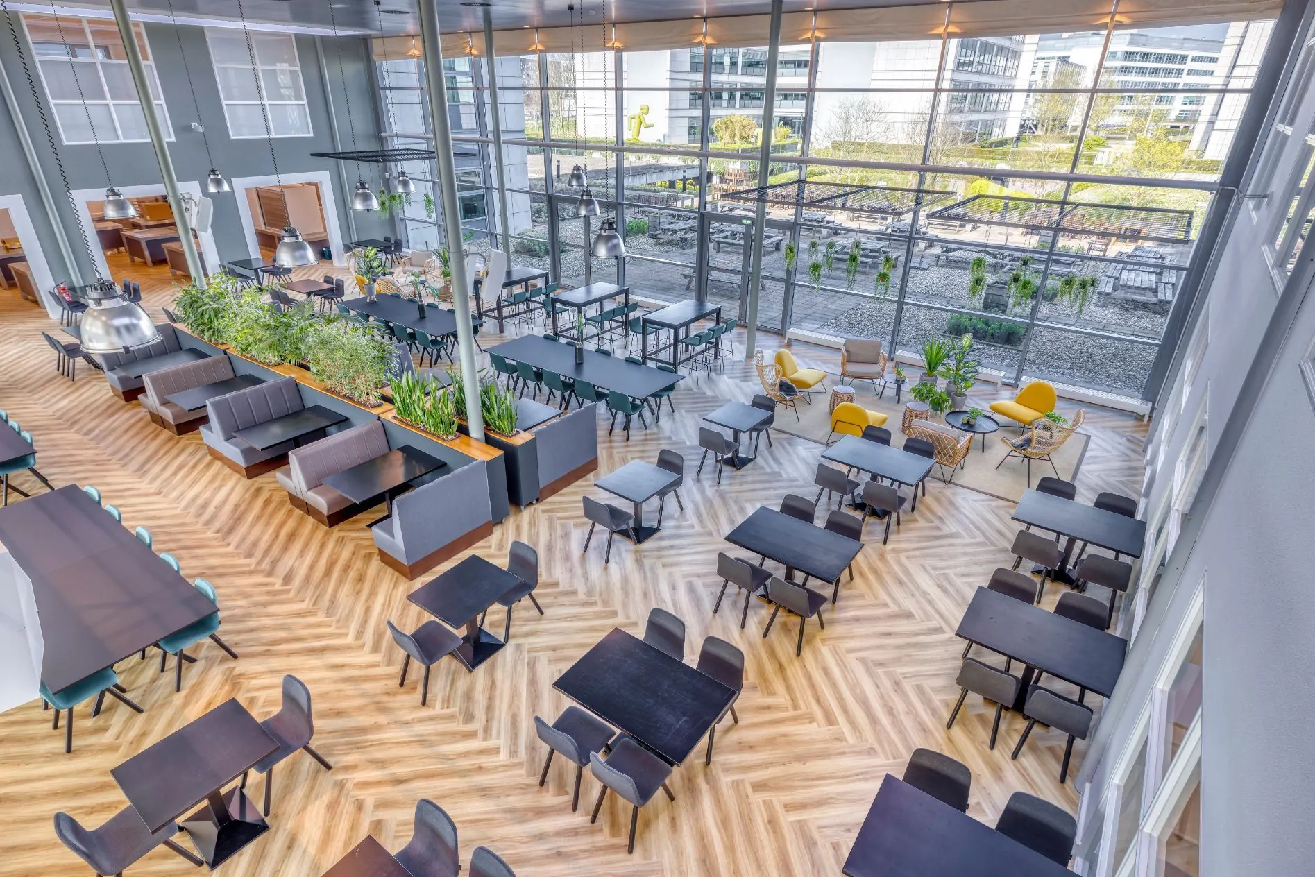 Moderne, ruim opgezette bedrijfsrestaurant aan de Spicalaan met grote raampartijen, diverse zitplekken en uitzicht op een groen buitenterras.