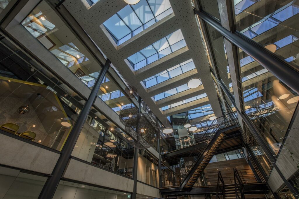 Modern atrium met glazen dak, stalen trappen en kantoren aan de Fokkerstraat.