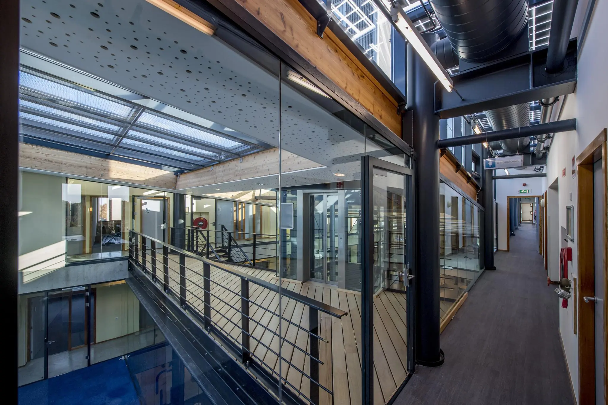 Modern kantoorinterieur aan de Fokkerstraat met glazen wanden, houten details en industriële plafondconstructie.